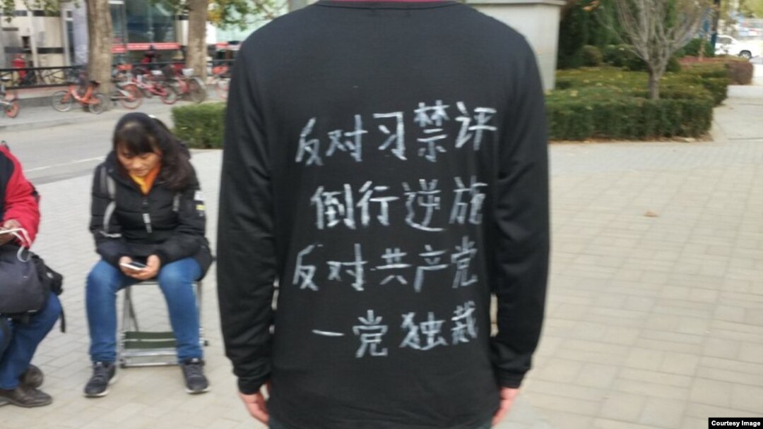 原北大保安张盼成的友人、留澳海归中国公民祁怡元（网名路西法）的图片，他的上衣背后写着：“反对习禁评倒行逆施！反对共产党一党独裁！”