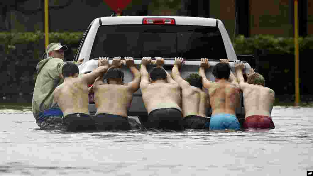 Des habitants de Houston poussent un pick-up bloqué dans une rue inondée, le 27 août 2017.