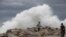 A tourist poses for a photo in front breaking waves before the expected arrival of Hurricane Lorena, in Los Cabos, Mexico, Sept. 20, 2019.