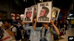 Demonstrators holding posters of Mexico's President Enrique Pena Nieto, right, and Attorney General, Jesus Murillo Karam, left, march in protest for the disappearance of 43 students in the state of Guerrero, in Mexico City, Nov. 5, 2014. 