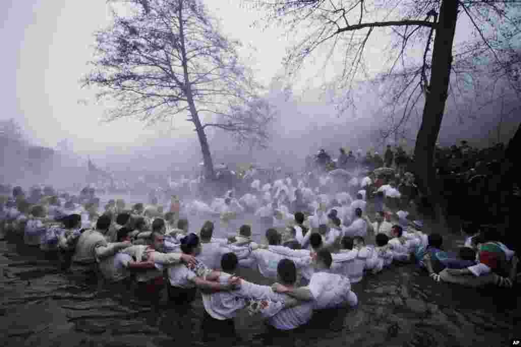 Believers sing and dance in the river Tundzha, as they celebrate Epiphany day in the town of Kalofer, Bulgaria  Friday, Jan. 6, 2012.  Traditionally, an Eastern Orthodox priest throws a cross in the river and it is believed that the one who retrieves it w