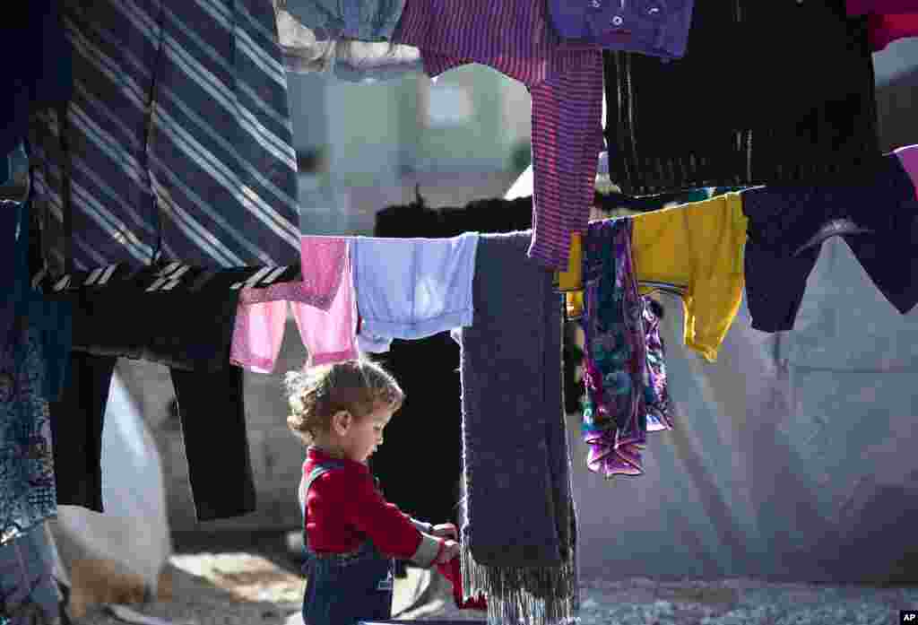 A Syrian Kurdish refugee child from the Kobani area handles laundry at a camp in Suruc, Nov. 12, 2014.