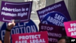 FILE - People hold up signs in favor of legal abortion during a protest against abortion bans, May 21, 2019, outside the Supreme Court in Washington.