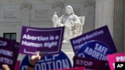 FILE - People hold up signs in favor of legal abortion during a protest against abortion bans, May 21, 2019, outside the Supreme Court in Washington.