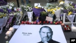 Buah apel segar dan bunga tanda dukacita diletakkan bersama poster Steve Jobs di luar gerai Apple di Beijing, Tiongkok (6/10).