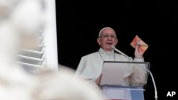 FILE - Pope Francis shows a crucifix during the Angelus noon prayer he delivers from the window of his studio overlooking St. Peter's Square at the Vatican, Sept. 16, 2018. 