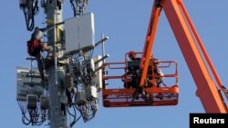 FILE - A Verizon contract crew installs 5G telecommunications equipment on a tower in Orem, Utah, Dec. 3, 2019.