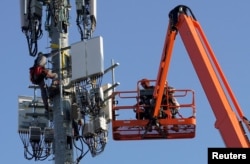 FILE - A Verizon contract crew installs 5G telecommunications equipment on a tower in Orem, Utah, Dec. 3, 2019.