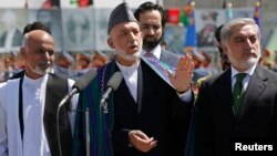 FILE - Afghan President Hamid Karzai (C) speaks during celebrations to commemorate Afghanistan's 95th anniversary of independence as he is flanked by presidential candidates Abdullah Abdullah (R) and Ashraf Ghani in Kabul, Afghanistan, August 2014.