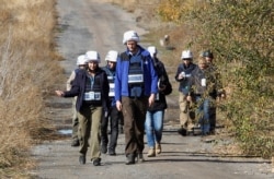 FILE - Members of the Organization for Security and Cooperation in Europe (OSCE) Special Monitoring Mission to Ukraine walk as they arrive for monitoring ahead of a proposed withdrawal of troops, in Petrіvske, Donetsk region, Ukraine, Oct. 9, 2019.
