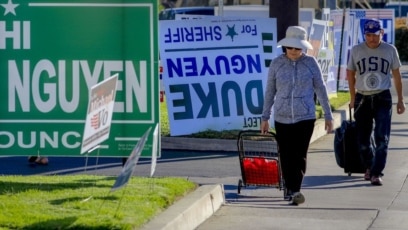 Người đi bộ dọc các panô tranh cử ở phố Bolsa, Westminster, quận Cam. Photo The Los Angeles Times. 