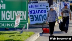 Người đi bộ dọc các panô tranh cử ở phố Bolsa, Westminster, quận Cam. Photo The Los Angeles Times. 