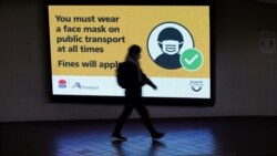 FILE - A person walks past a public health warning for passengers to wear face masks at a city center transit station during a lockdown to curb the spread of COVID-19 in Sydney, Australia, Aug. 17, 2021.