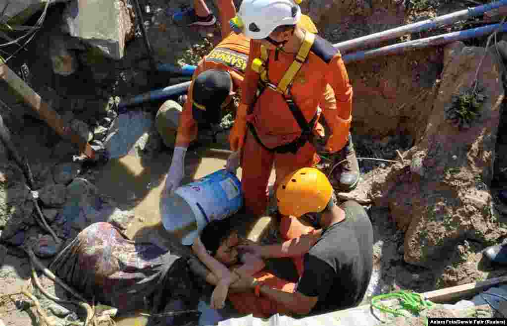 Search and rescue workers help rescue a person trapped in rubble following an earthquake and tsunami in Palu, Central Sulawesi, Indonesia, Sept. 30, 2018.