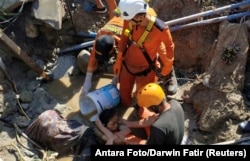 Search and rescue workers help rescue a person trapped in rubble following an earthquake and tsunami in Palu, Central Sulawesi, Indonesia, Sept. 30, 2018.