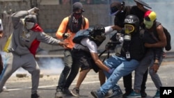 Demonstrators help a journalist who was injured in a leg while covering clashes between demonstrators and the Bolivarian National Guard during a protest in Caracas, April 10, 2017.