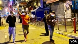 香港政府宣布1月25日傍晚6时开始，持阴性病毒检测证明的人士，可以登记离开佐敦封锁区，被禁足接近40小时的居民重获自由后离开封锁区时向传媒挥手。 (美国之音/汤惠芸)