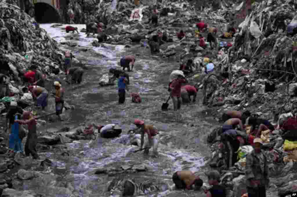 In this photo taken Wednesday Oct. 19, 2011, people search for scrap metal in contaminated water at the bottom of one of the biggest trash dumps in the city, known as "The Mine," in Guatemala City. Hundreds of informal workers descend daily into the moun