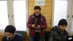 In this Jan. 30, 2020, photo, a Kashmiri journalist, center, browses the internet on his mobile phone inside the media center set up by government authorities in Srinagar, Indian controlled Kashmir. (AP Photo/ Dar Yasin)