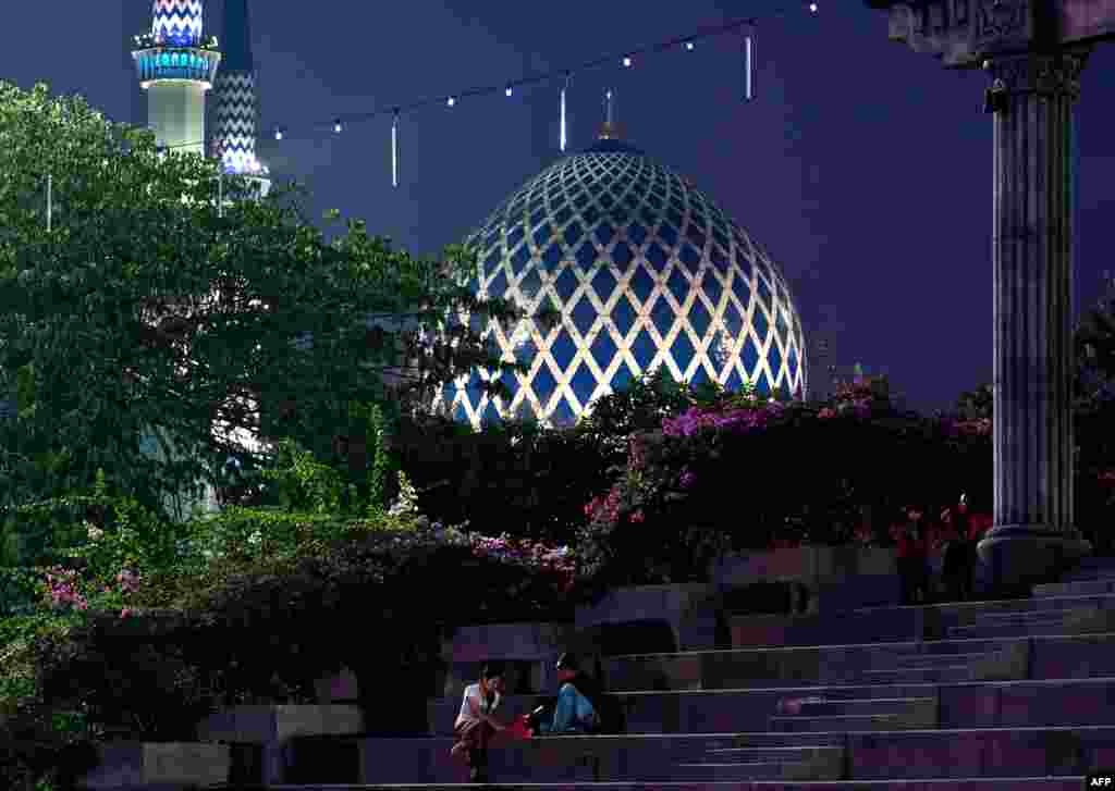 Malaysian Muslims break their fast during the holy month of Ramadan with the backdrop of a mosque in Shah Alam.