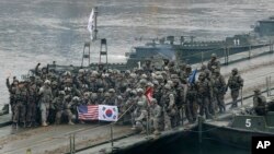 Tentara AS dan Korea Selatan berpose di jembatan terapung di Sungai Hantan setelah operasi penyeberangan sungai, bagian dari latihan militer gabungan tahunan antara Korea Selatan dan Amerika Serikat di Yeoncheon, Korea Selatan. (Foto: AP)