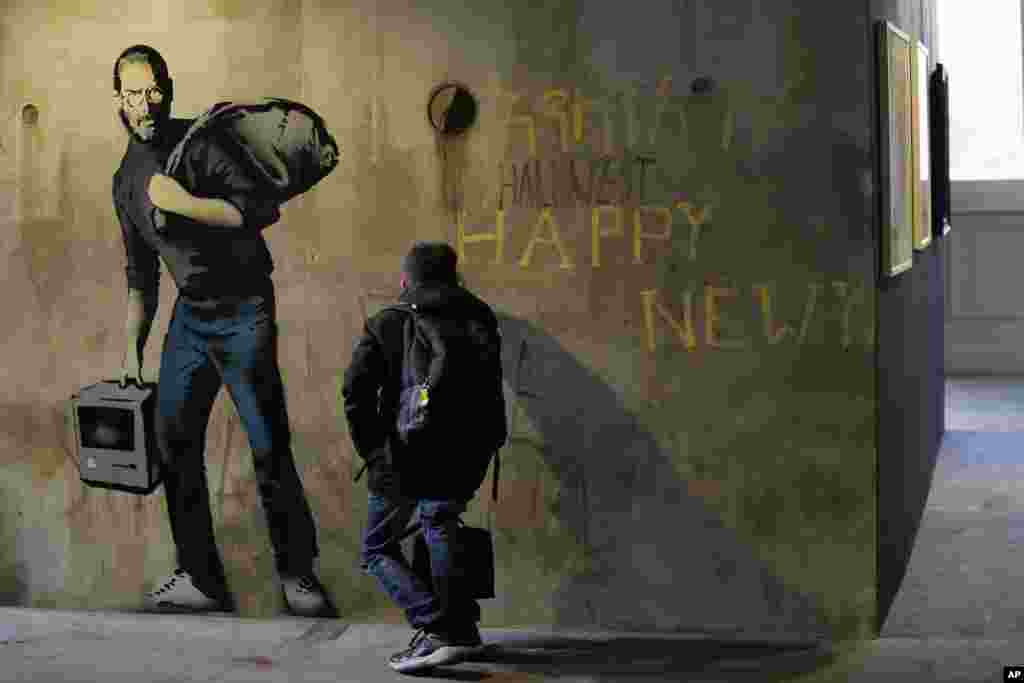 A visitor looks at &quot;Steve Jobs&quot;, a reproduction of a mural by British artist Banksy, during the unveiling of the &quot;The World of Banksy, The Immersive Experience&quot; exhibition, in Milan, Italy.