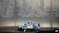 Flowers are placed by portraits of slain journalists Alexander Rastorguyev, Kirill Radchenko and Orkhan Dzhemal, at the Russian journalists Union building in Moscow, Russia, Wednesday, Aug. 1, 2018. 