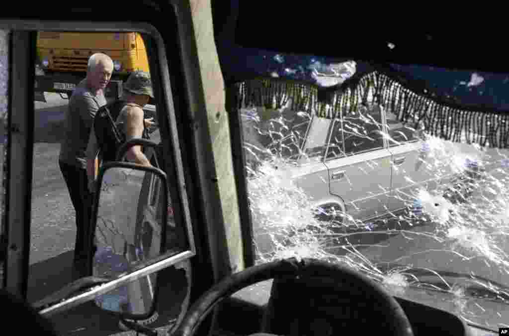 A Pro-Russian rebel checks the car of a local citizen. It was here that at least 12 militiamen fighting alongside government troops against pro-Russian separatist rebels were killed in an ambush, on the outskirts of Donetsk, eastern Ukraine, Aug. 13, 2014.