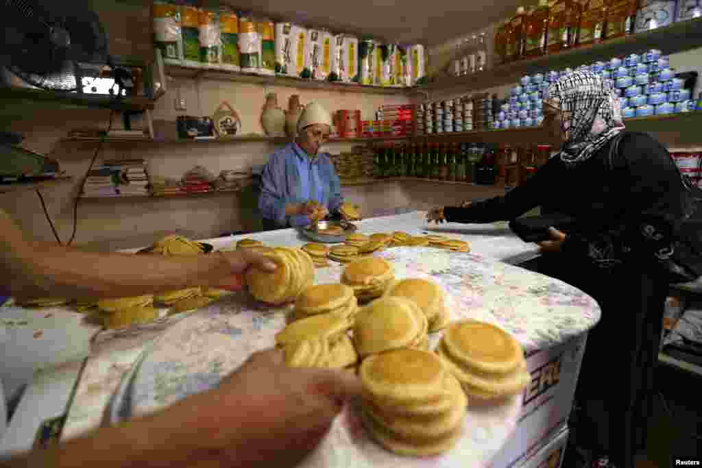 Seorang perempuan Palestina membeli qatayef, penganan manis tradisional yang dimakan saat bulan puasa, di Ramallah, Tepi Barat (10/7). (Reuters/Mohamad Torokman)