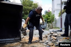 An Israeli police explosives expert carries the remains of a rocket fired from Gaza that landed in Ashdod, Israel, July 14, 2014.