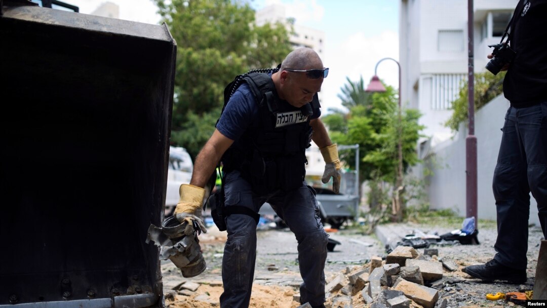 Seorang polisi Israel tengah membawa kepingan roket dari Gaza yang berhasil ditembak dan jatuh di kawasan Ashdod (14/7). Militer Israel mengatakan telah menembak jatuh sebuah drone yang terbang memasuki Israel dari Gaza.