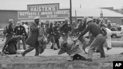 FILE - A state trooper swings a billy club at John Lewis, right foreground, chairman of the Student Nonviolent Coordinating Committee, to break up a civil rights voting march in Selma, Alabama, March 7, 1965.