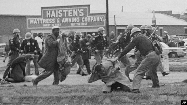 FILE - A state trooper swings a billy club at John Lewis, right foreground, chairman of the Student Nonviolent Coordinating Committee, to break up a civil rights voting march in Selma, Alabama, March 7, 1965.