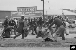 FILE - A state trooper swings a billy club at John Lewis, right foreground, chairman of the Student Nonviolent Coordinating Committee, to break up a civil rights voting march in Selma, Ala., March 7, 1965.