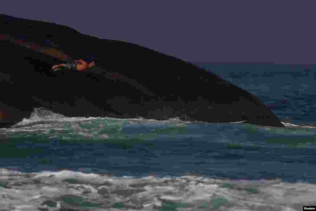 A surfer dives into the ocean on the first day of beaches reopening for sports only amid the coronavirus disease (COVID-19) outbreak, at Ipanema beach in Rio de Janeiro, Brazil.