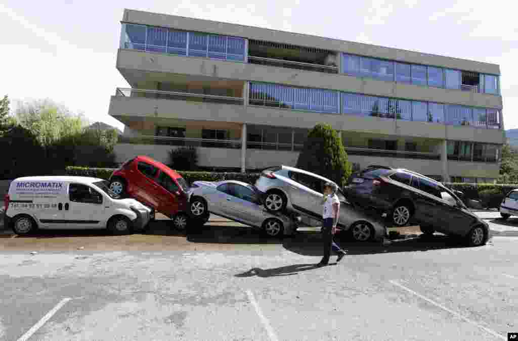 A man walks by cars piling up after floods in Mandelieu la Napoule, southern France. Flash flooding around the French Riviera has killed more than a dozen people, some drowned in a retirement home and others trapped in cars and campsites.
