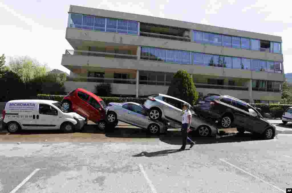 A man walks by cars piling up after floods in Mandelieu la Napoule, southern France. Flash flooding around the French Riviera has killed more than a dozen people, some drowned in a retirement home and others trapped in cars and campsites. 