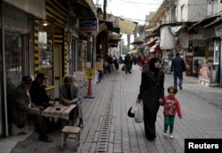 A Syrian woman and her child walk along a street in the neighborhood of Basmane, which is filled with transient migrants on their way to Europe, in the Aegean port city of Izmir, western Turkey, March 8, 2016.