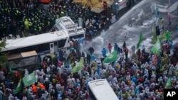 South Korean riot police officers spray water cannons as police officers try to break up protesters who tried to march to the Presidential House after a rally against government policy in Seoul, South Korea, Nov. 14, 2015. 