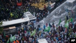 Polisi anti huru-hara Korea Selatan menyemprotkan air sementara polisi berusaha membubarkan demonstran yang mencoba berpawai ke kediaman presiden setelah pawai menentang peraturan pemerintah di Seoul, Korea Selatan, 14 November 2015. 