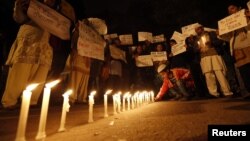 A boy places a candle as demonstrators hold placards during a candlelight march for a gang rape victim, who was assaulted in New Delhi, January 16, 2013. 