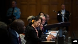 Myanmar's leader Aung San Suu Kyi, center, and Gambia's Justice Minister Aboubacarr Tambadou, left, listen to judges in the court room of the International Court of Justice for the first day of three days of hearings in The Hague, Dec. 10, 2019.