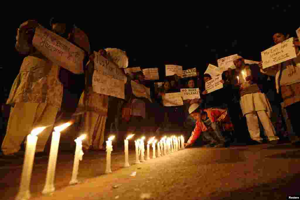 A boy places a candle as demonstrators hold placards during a candlelight march for a gang rape victim, who was assaulted in New Delhi, January 16, 2013.