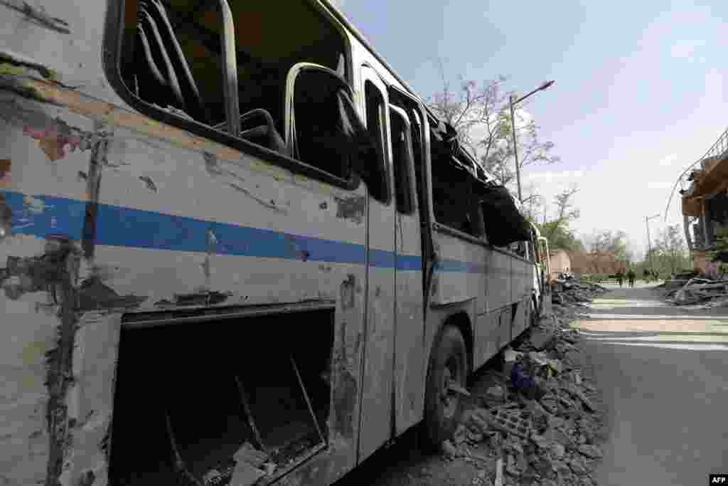 Một chiếc xe bus bị phá hủy gần đống đổ nát của Trung tâm Nghiên cứu Khoa học Syria, bị tấn công bởi các cuộc không kích của liên quân Mỹ, Anh và Pháp tại Barzeh, gần thủ đô Damascus, Syria, ngày 14 tháng 4 năm 2018. 