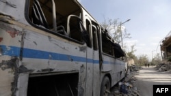 This April 14, 2018 photo shows a destroyed bus near the wreckage of a building described as part of the Scientific Studies and Research Center (SSRC) in the Barzeh district, north of Damascus, Syria.