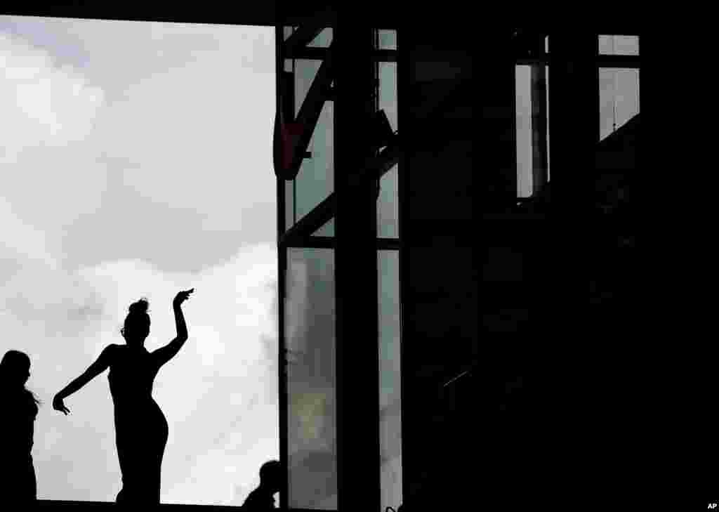 A girl dances in front of a window at the Porta Nuova business district in Milan, Italy.