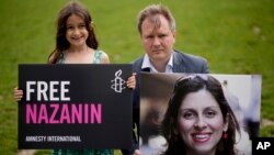FILE - Richard Ratcliffe, husband of imprisoned British-Iranian Nazanin Zaghari-Ratcliffe and their seven year-old daughter Gabriella pose for the media with a photo of her, in London, Britain, Sept. 23, 2021. 