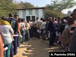 Workers line up along a busy intersection in the business hub of Gurgaon near New Delhi.