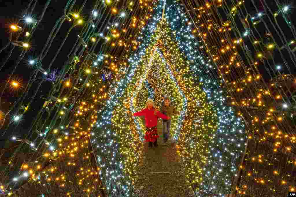 Children walk past 200,000 lights that decorate a winter wonderland at Naumkeag, part of the land managed by the Trustees of Reservations, in Stockbridge, Massachusetts, Dec. 13, 2020.