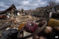 Para pemilik rumah dan tetangganya membersihkan puing-puing rumahnya yang hancur diterjang roket Rusia di desa Maxymilianivka, Ukraina, Selasa, 21 Februari 2023. (Foto: AP)